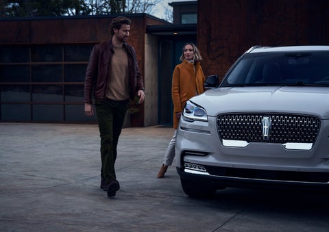 A man and a woman approaching a 2024 Lincoln Aviator® SUV, which illuminates certain lights when they are close | Courtesy Lincoln in Altoona PA