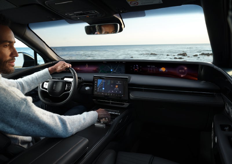 A driver of a parked 2024 Lincoln Nautilus® SUV takes a relaxing moment at a seaside overlook while inside his Nautilus. | Courtesy Lincoln in Altoona PA